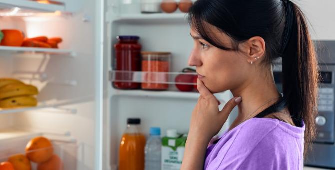 Une femme regarde le contenu de son réfrigérateur