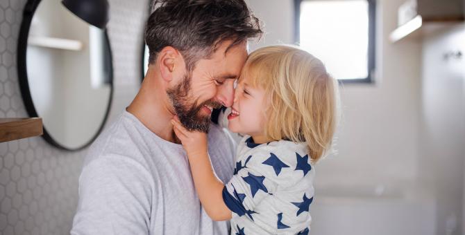 un père souriant serrant son enfant souriant dans ses bras