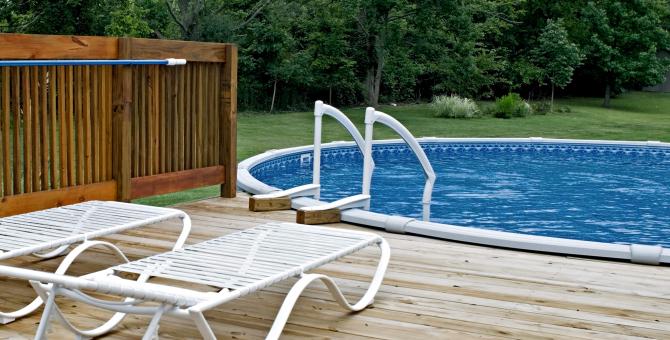 Une terrasse avec deux chaises longues et une piscine hors terre