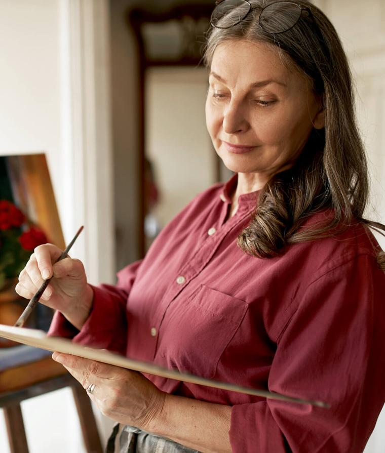Une femme âgée fait de la peinture sur un chevalet